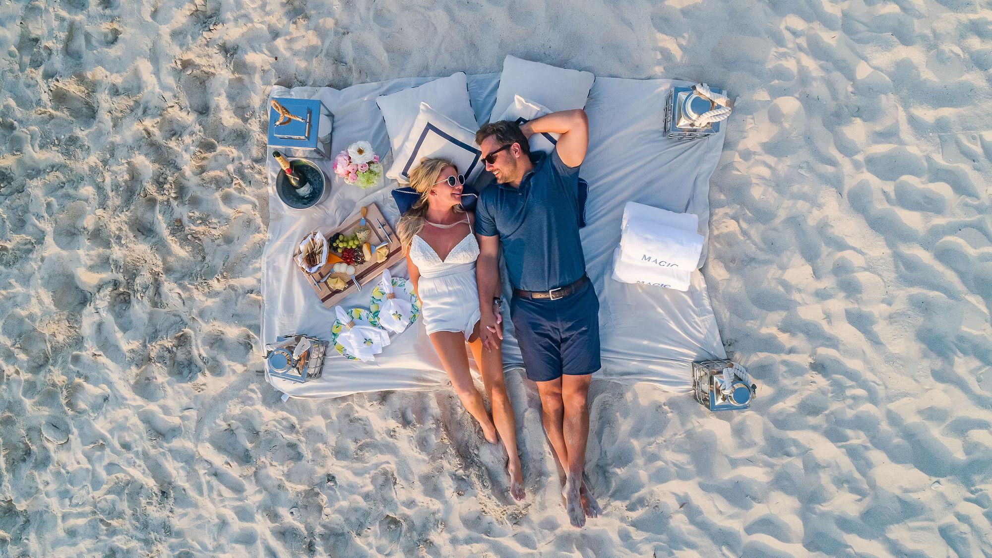 A picturesque beach setup beside the MAGIC yacht, featuring an elegantly arranged table and seating for a luxurious outdoor picnic experience. | MAGIC yacht, beach setup, outdoor dining, luxury lifestyle | Fraser Yachts