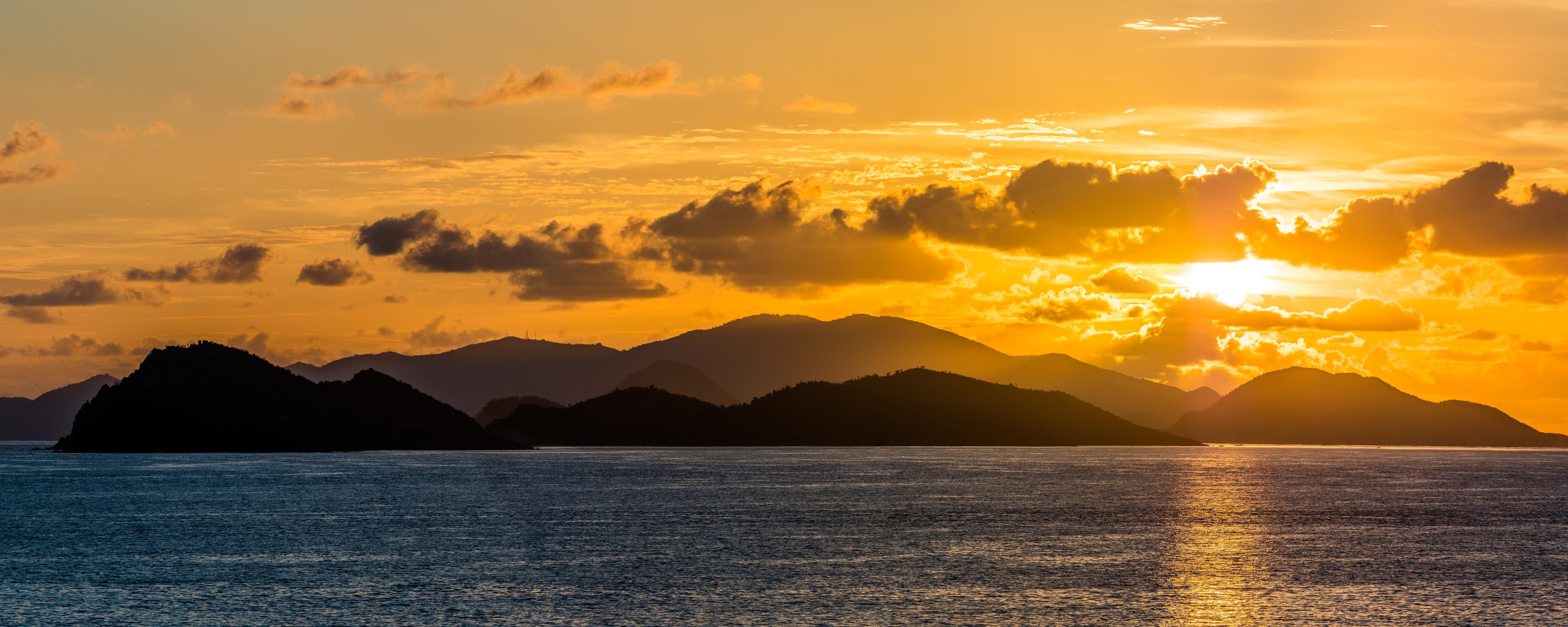 Sunrise over the US Virgin Islands in the Caribbean Sea—golden light illuminates tropical waters and rolling hills, marking the perfect start to a luxury yacht charter day | Fraser Yachts