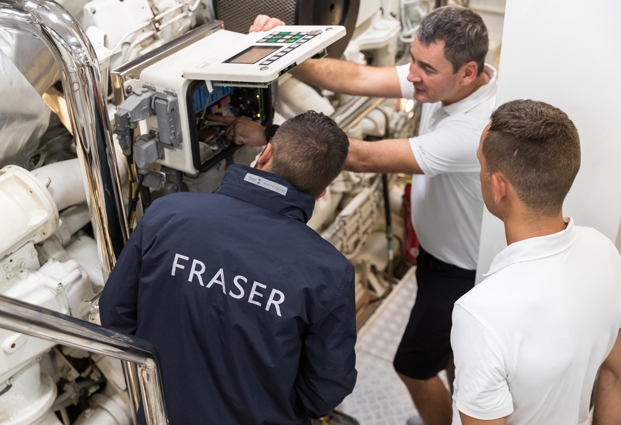 Three workers inspecting the engine of a Formosa yacht during the construction phase, ensuring quality and performance. | yacht construction, engine inspection, Formosa yacht, boat building | Fraser Yachts