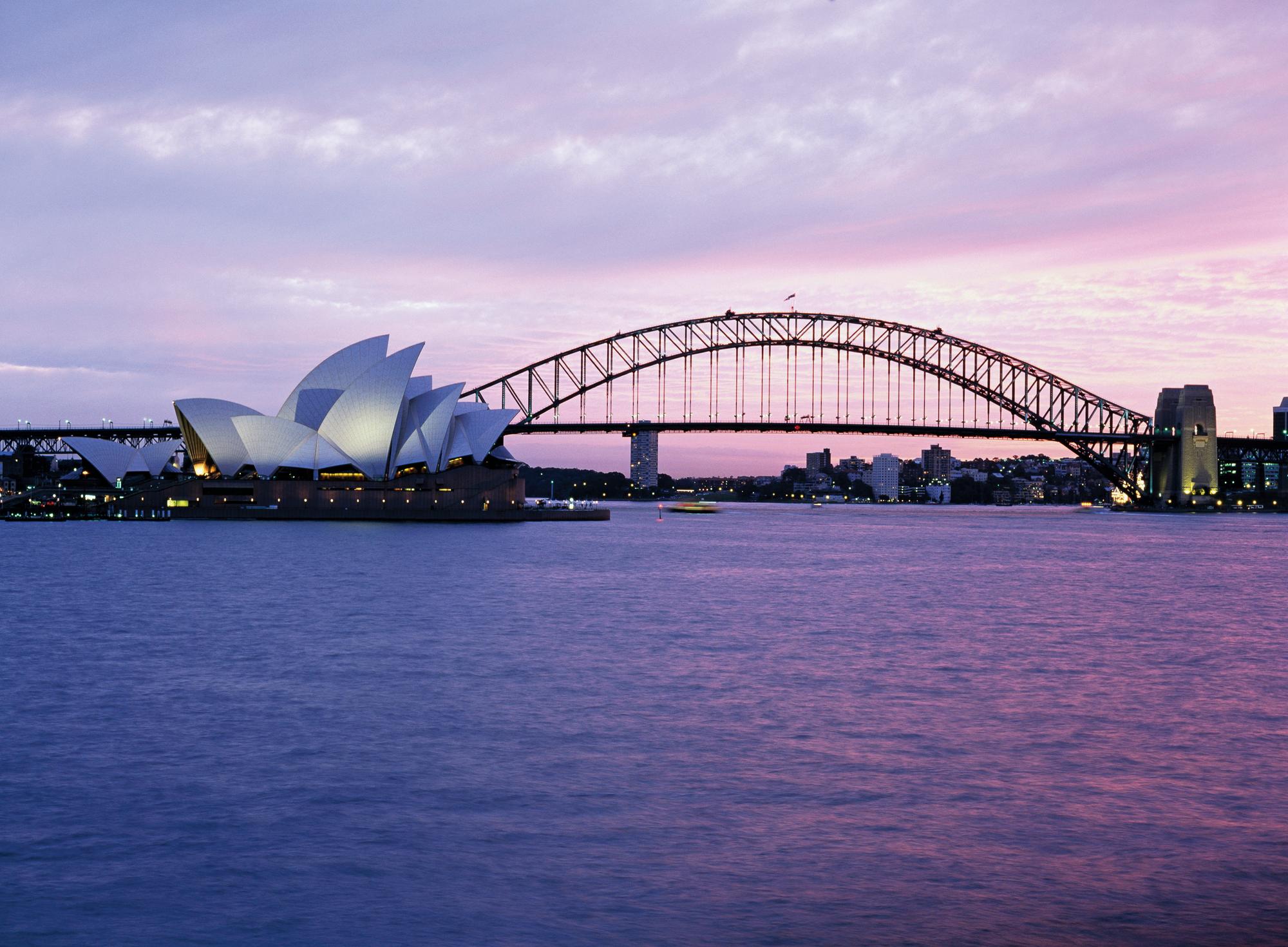 Experience the iconic Sydney Opera House illuminated in purple light in Australasia with Fraser Yachts. | Australasia, Sydney, Opera House, purple light, yacht charter | Fraser