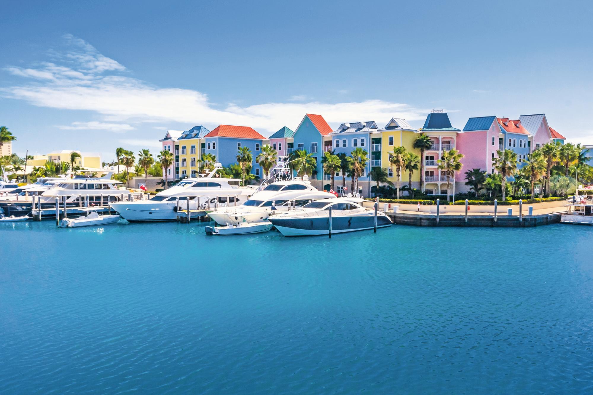 Immerse yourself in the vibrant marina scene surrounded by colorful houses in the Bahamas with Fraser Yachts. | Caribbean, Bahamas, marina, colored houses, yacht charter | Fraser