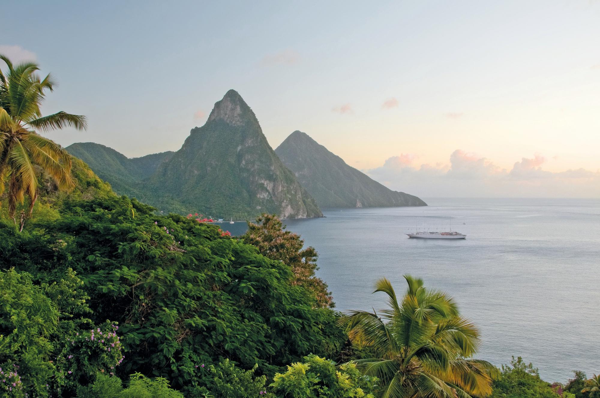 Witness the majestic sunrise over the iconic Twin Pitons in St. Lucia, Caribbean, with Fraser Yachts. | Caribbean, St. Lucia, Twin Pitons, sunrise, yacht charter | Fraser