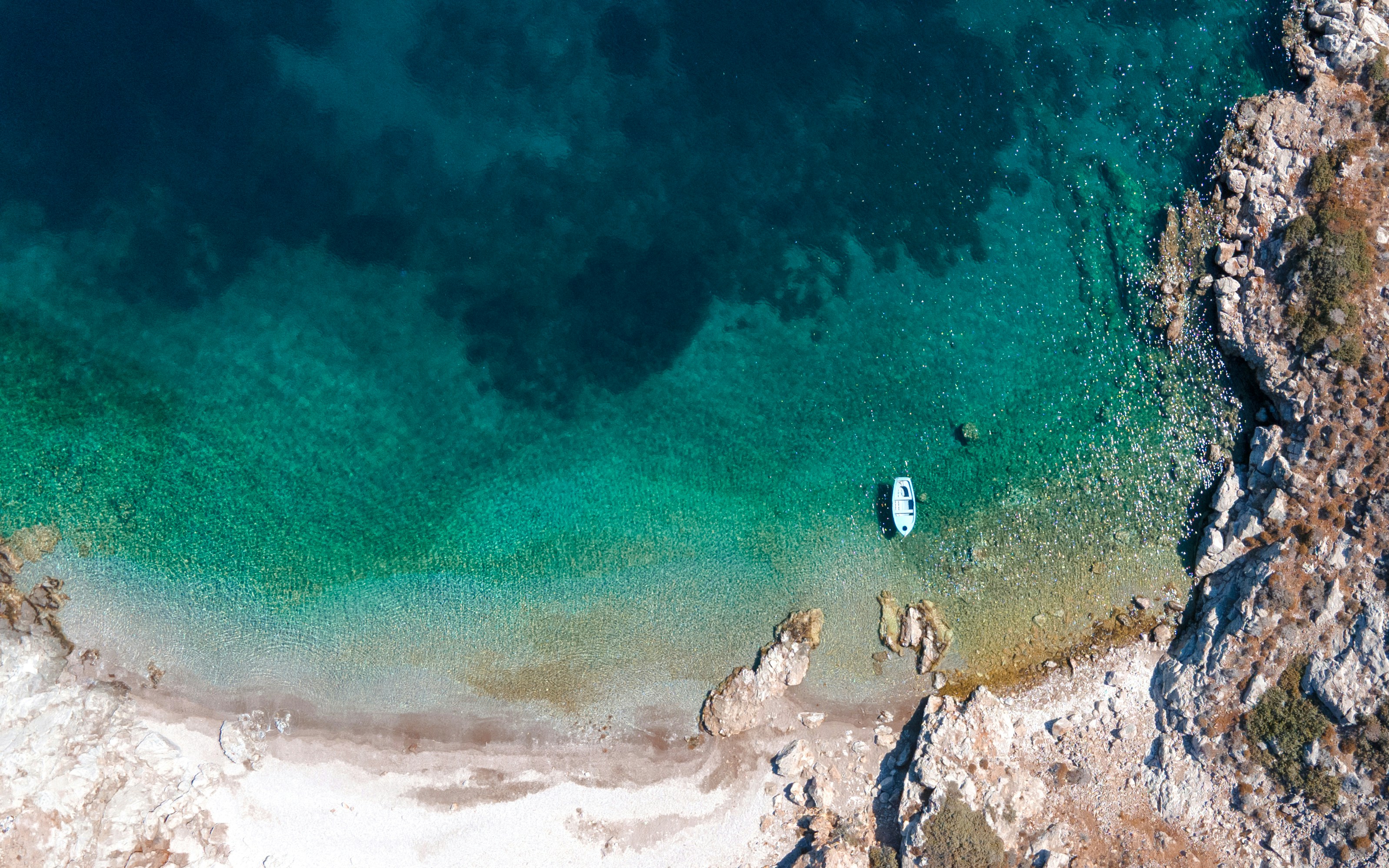 Aerial view of a secluded beach in the Greek Cyclades—clear turquoise waters and rocky coastline create a serene Mediterranean setting for yacht anchoring | Fraser Yachts