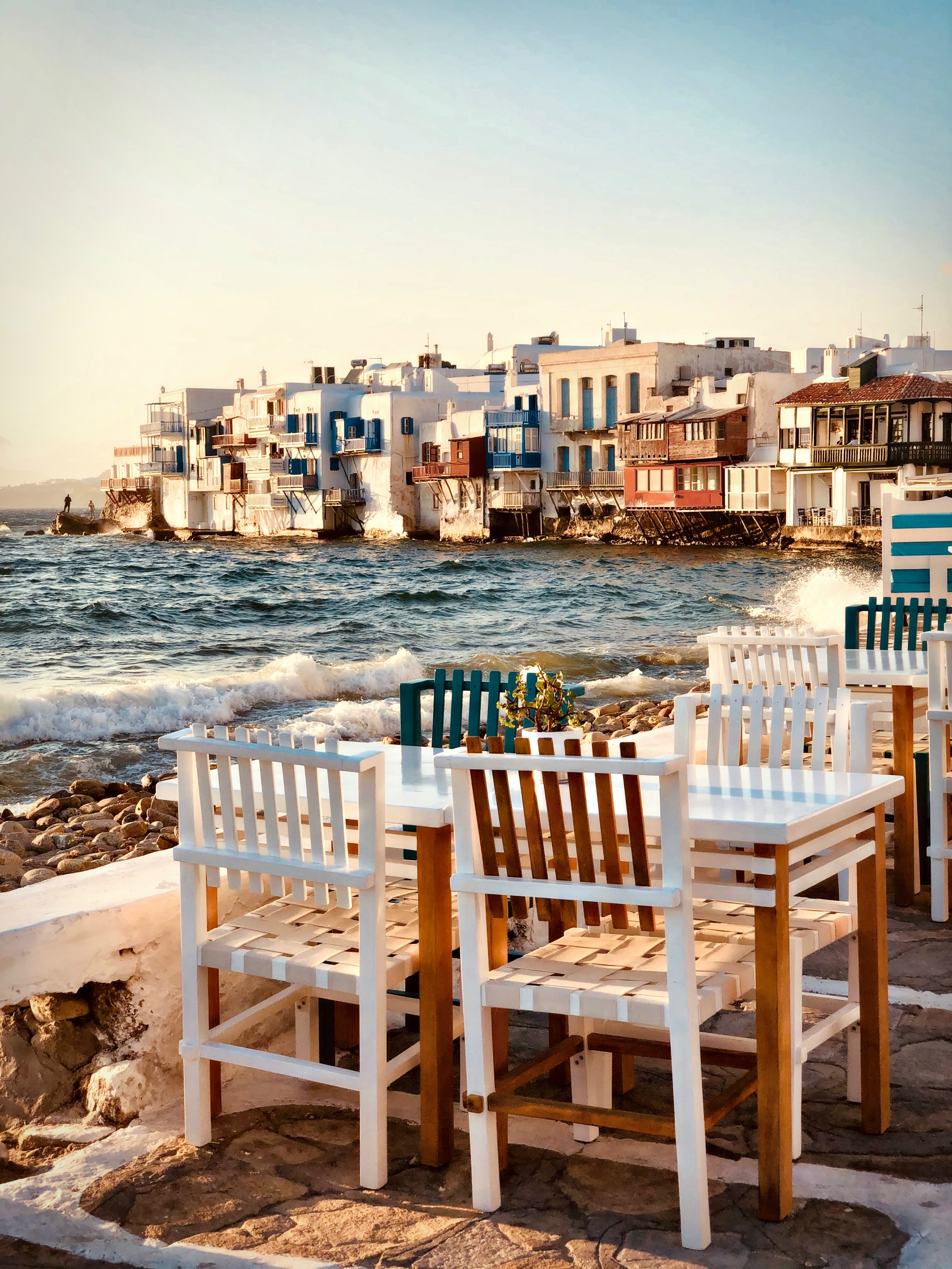 Seafront dining in Mykonos, Greece—tables overlooking the sea and whitewashed houses create a relaxed Mediterranean lifestyle experience for yacht guests | Fraser Yachts