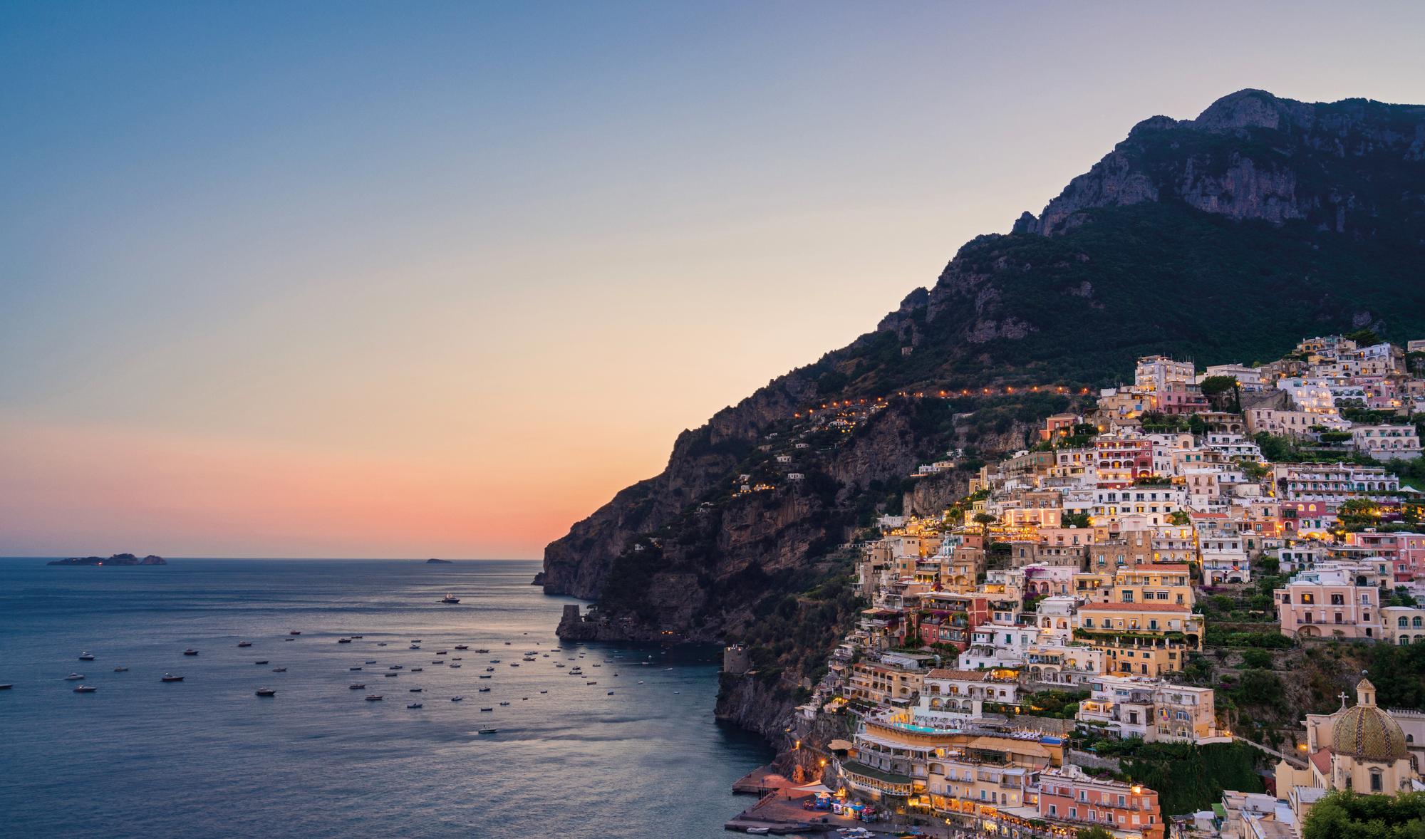 Witness the enchanting beauty of Positano by night, as the sunset paints the sky with captivating hues, with Fraser Yachts. | Mediterranean, Italy, Positano, sunset, night view, yacht charter | Fraser