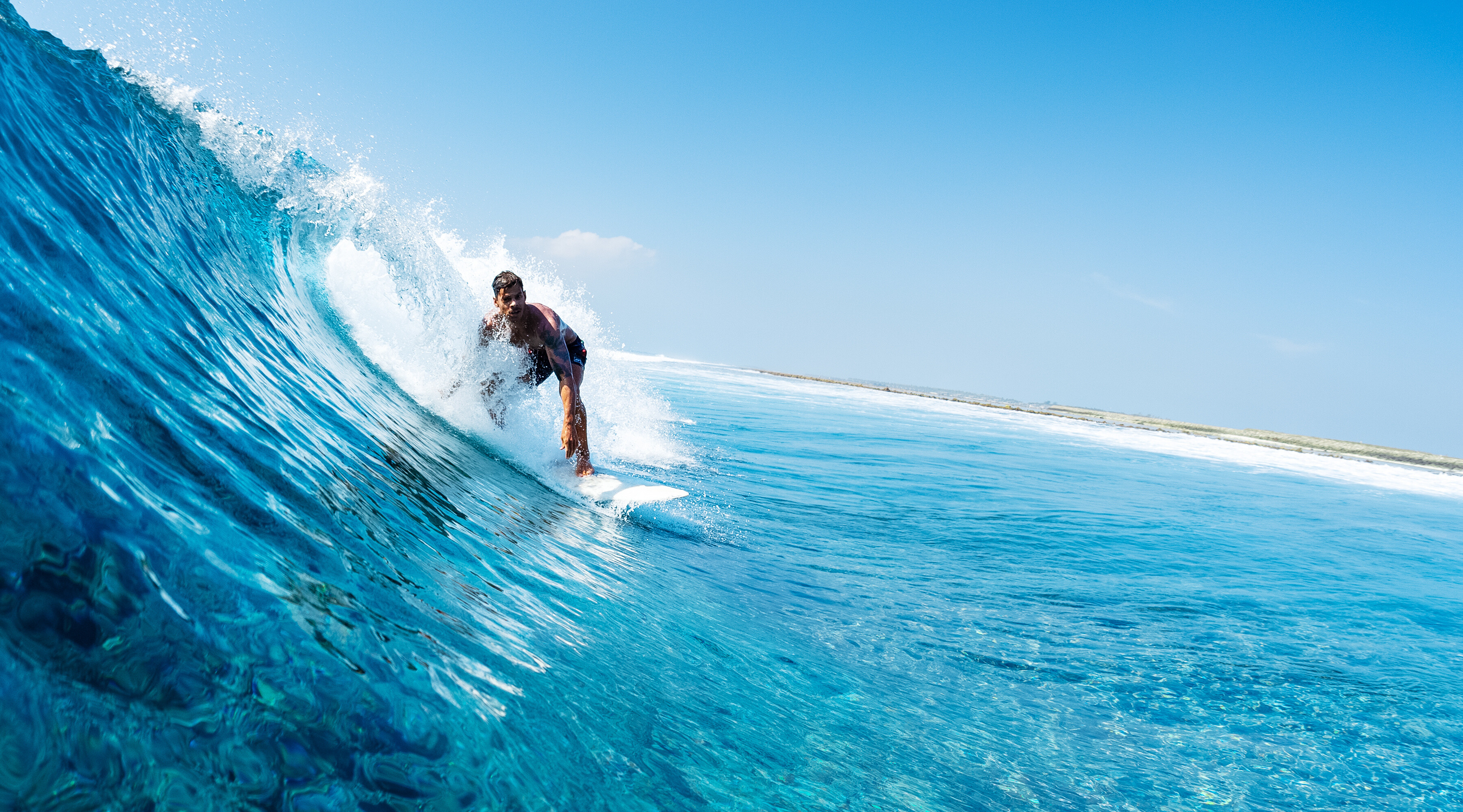 "Experience the thrill of surfing as a surfer carves through a stunning blue wave in tropical waters. Perfect for adventure seekers and ocean lovers, this image captures the excitement and beauty of the surf lifestyle