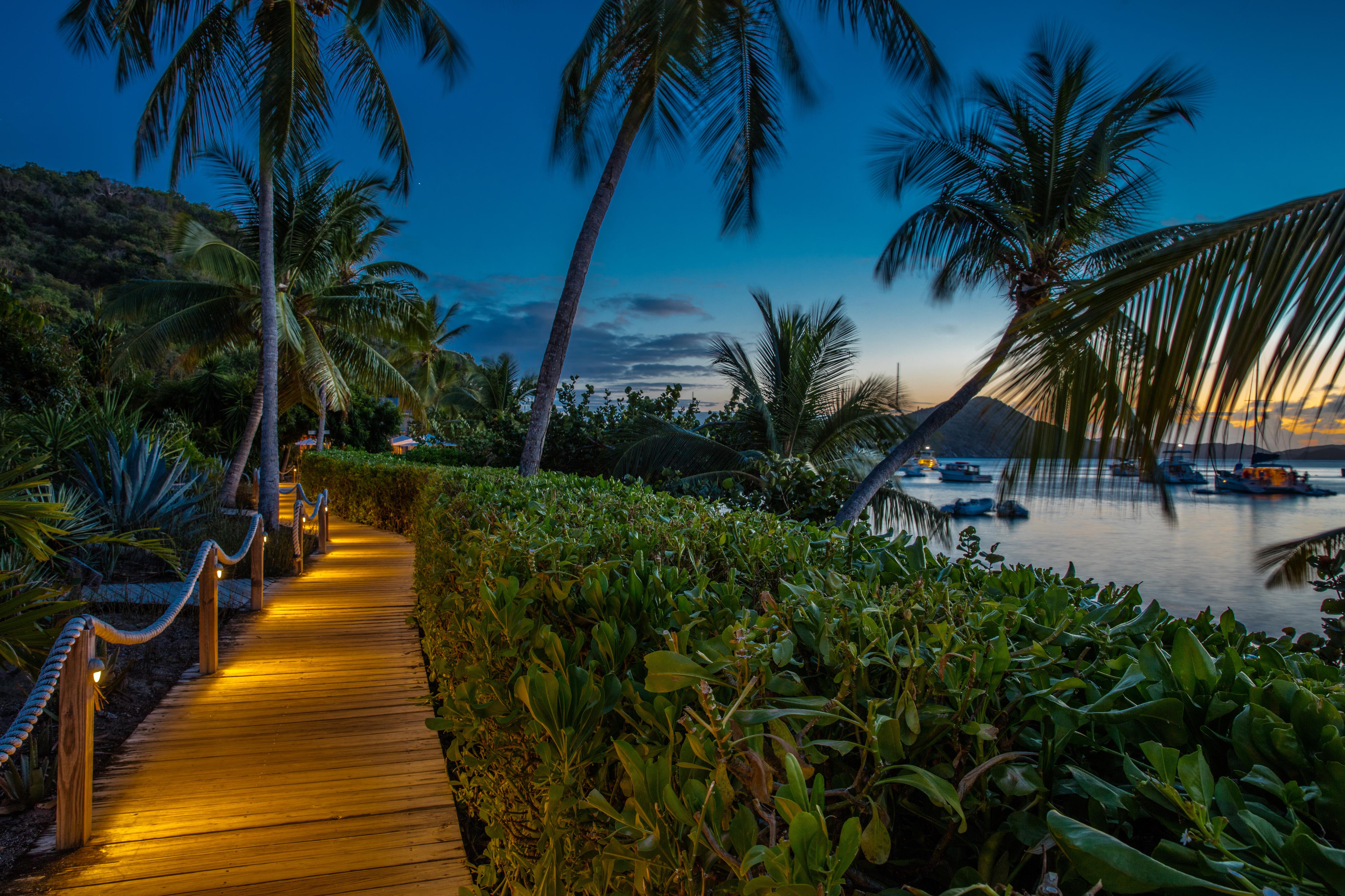 Cooper Island at dusk in the British Virgin Islands—palm-lined walkways, soft twilight, and calm anchorage create a serene tropical escape near Peter Island | Fraser Yachts