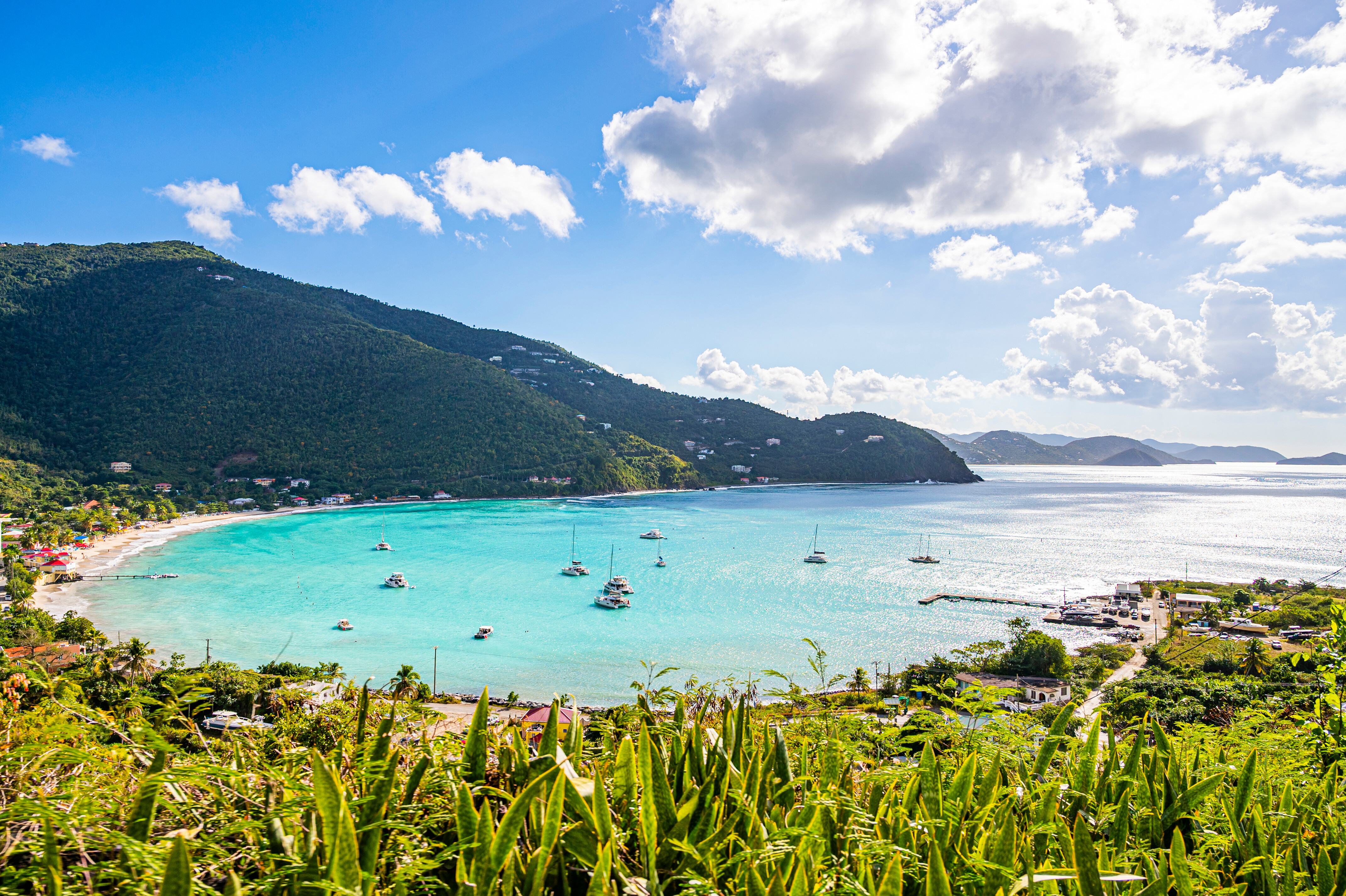 Cane Garden Bay on Tortola, British Virgin Islands—tropical paradise with turquoise waves, lush mountains, palm-lined shores, and yachts anchored in this idyllic Caribbean escape | Fraser Yachts