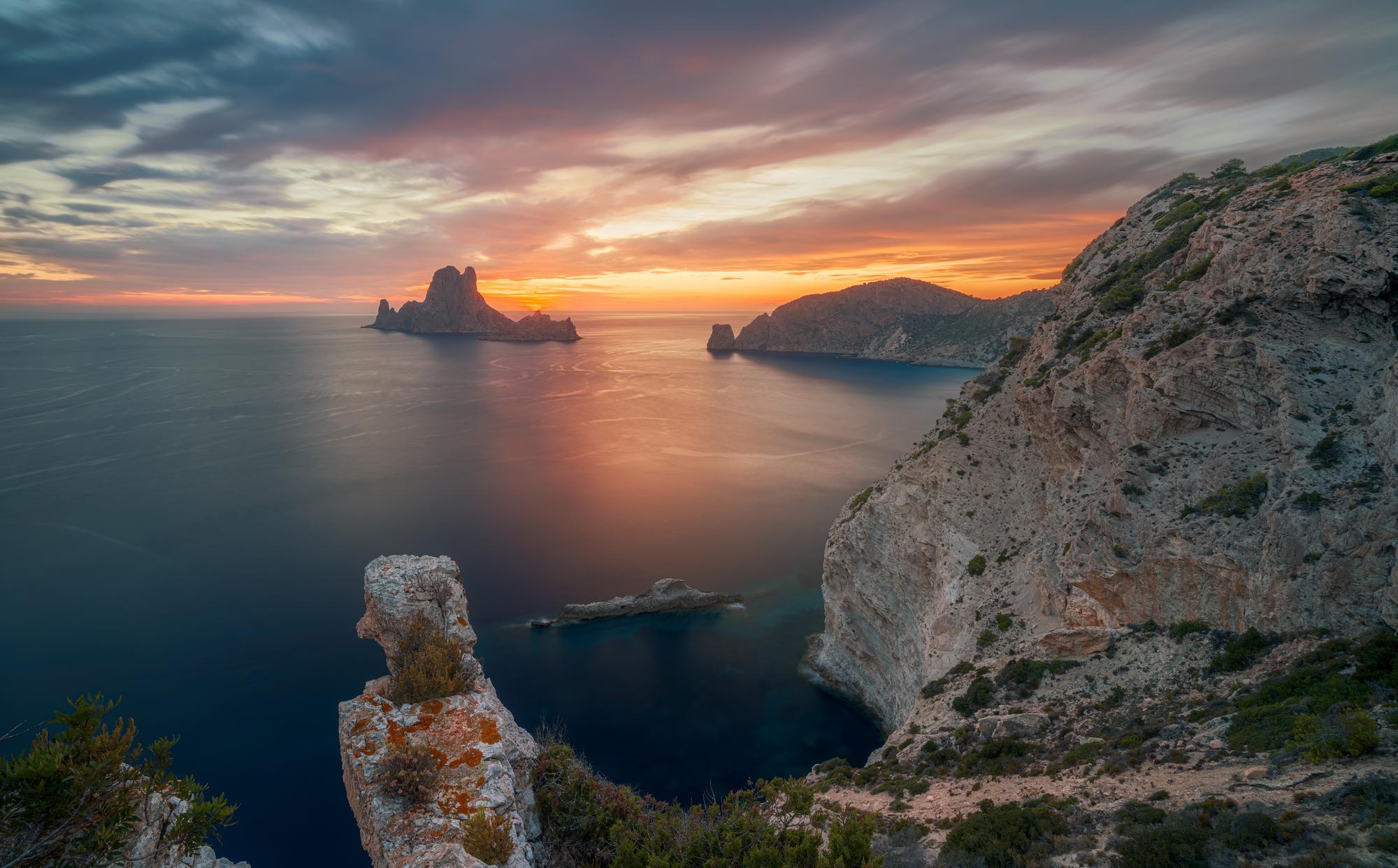 Experience the stunning landscape of Es Vedra Island in Spain's Balearic Islands, known for its beautiful sunsets, dramatic cliffs, and picturesque clouds | Beautiful, landscape, sunset, cliff, cloud, Es Vedra Island, Balearic Islands, Spain | Fraser