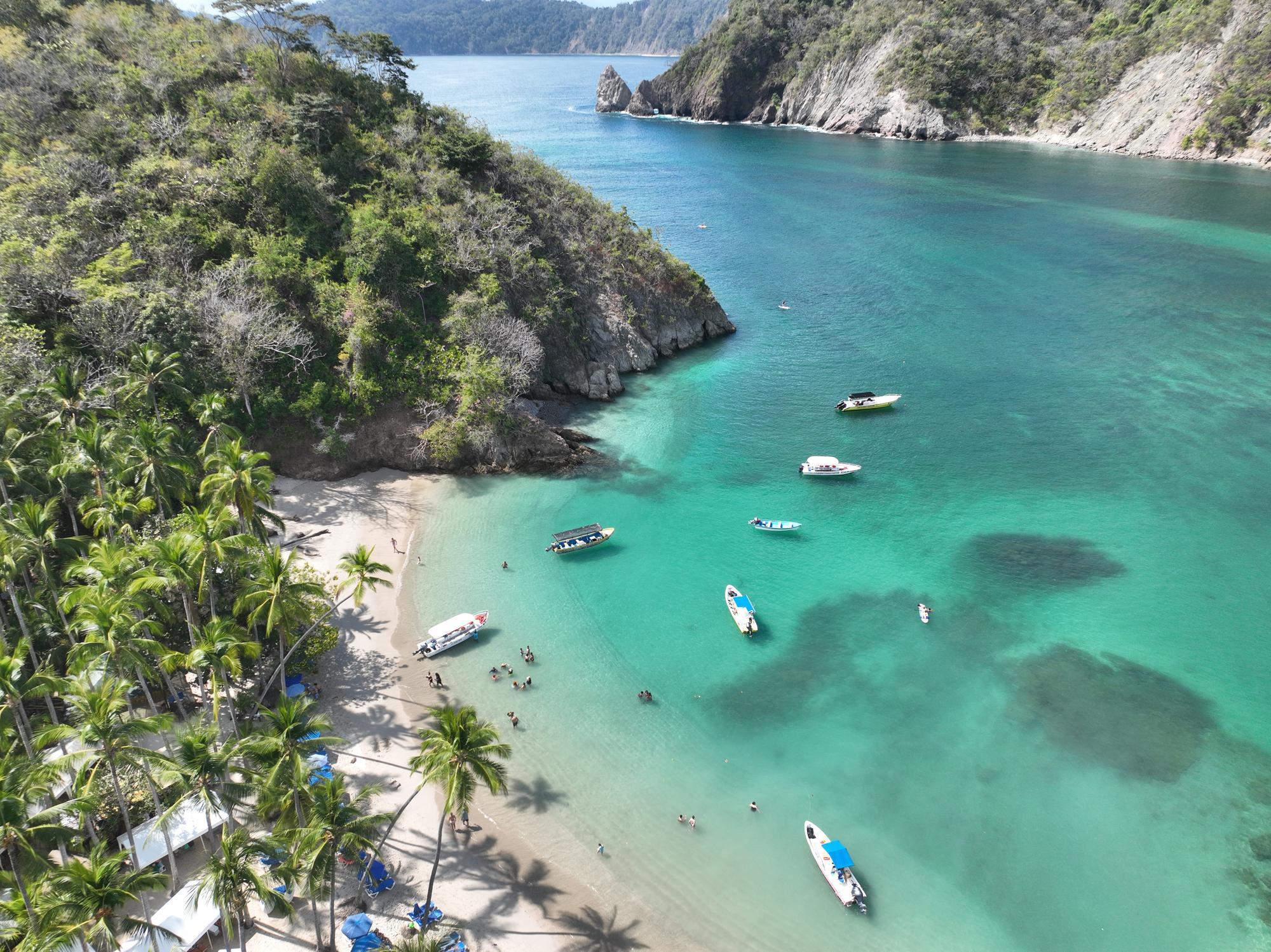 Enjoy a breathtaking aerial view of Tortuga Island's coastline, featuring white sand beaches, turquoise waters, and beautiful palms. A perfect vacation spot. | Aerial, Coastline, Sand, Beautiful, Boats, Beach, Turquoise, Palms | Fraser