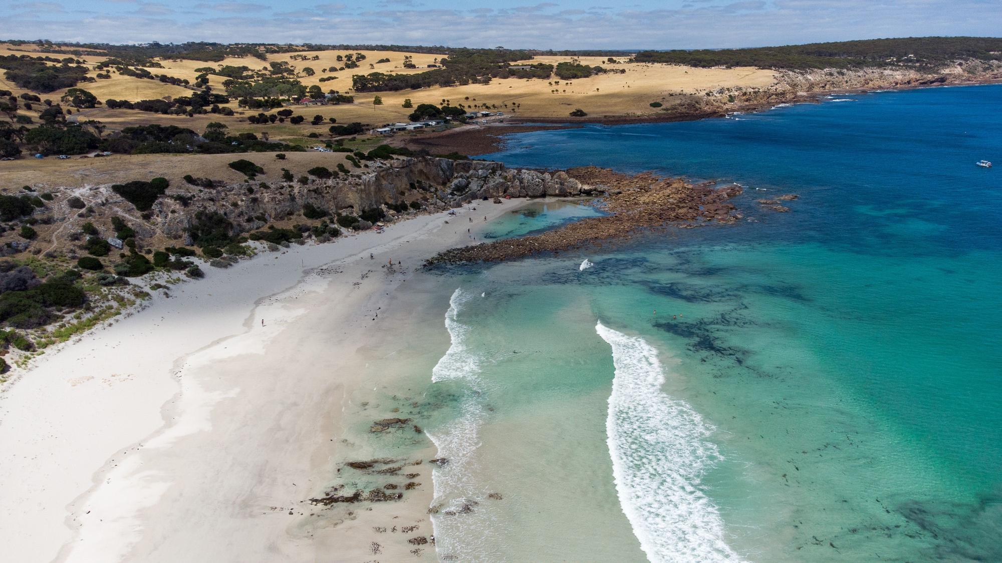 Enjoy the perfect sunny day at Stokes Bay with an aerial perspective of the bay, seascape, and surfers in the beautiful Great Barrier Reef | Aerial view, bay, seascape, surfers, sunny day | Fraser