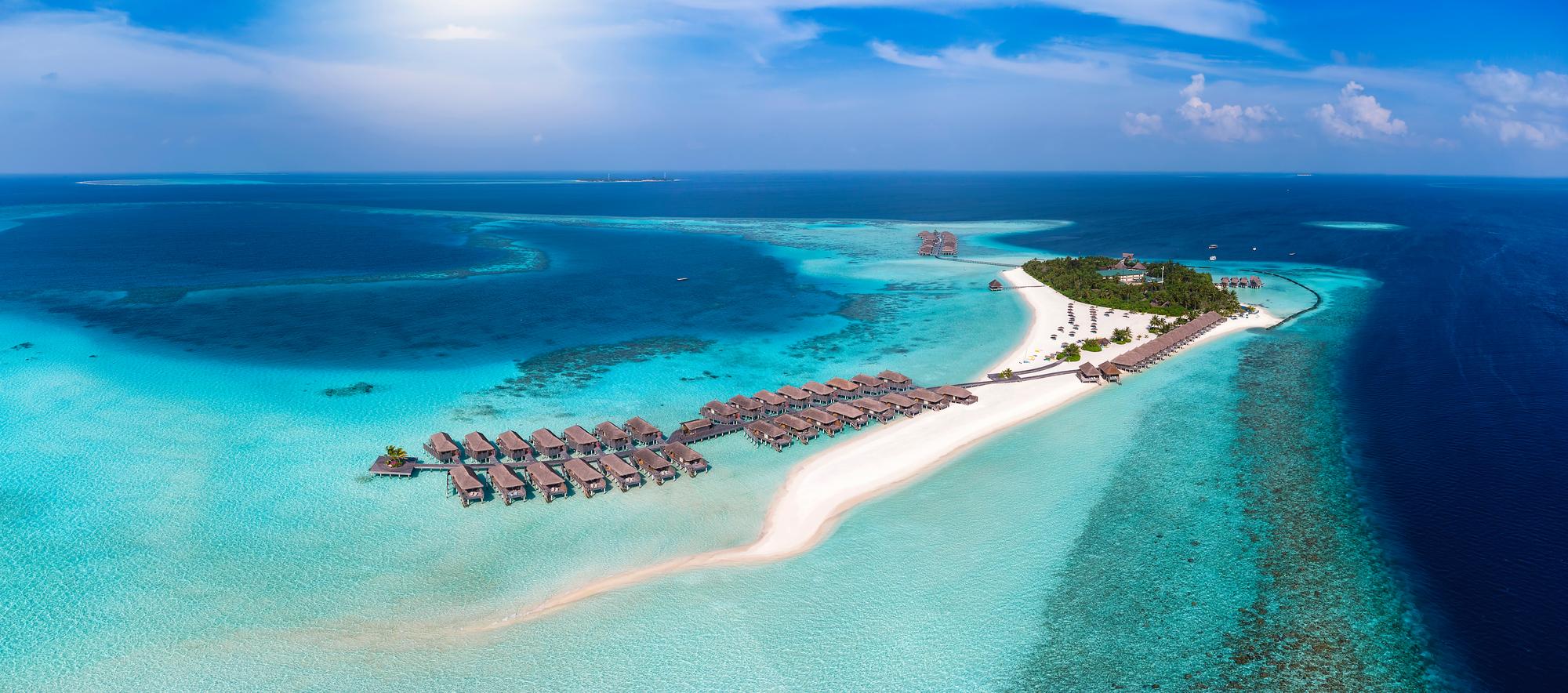 Discover the beauty of the Maldives from above with this aerial view of an exotic island featuring palm trees, bungalows, and sandy beaches for a perfect vacation. | Aerial, Beauty, Palm, Exotic, Island, Vacation, Bungalows, Sand | Fraser