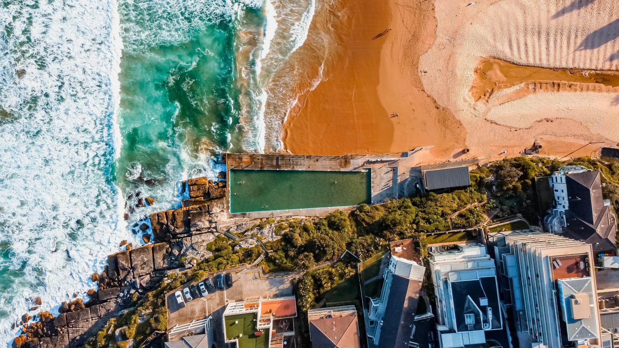 Explore Manly Beach: Aerial shot showcasing the beach, coast, and scenic waves splashing over stones | Aerial, Beach, Coast, Scenic, Splashing, Stones, Waves | Fraser