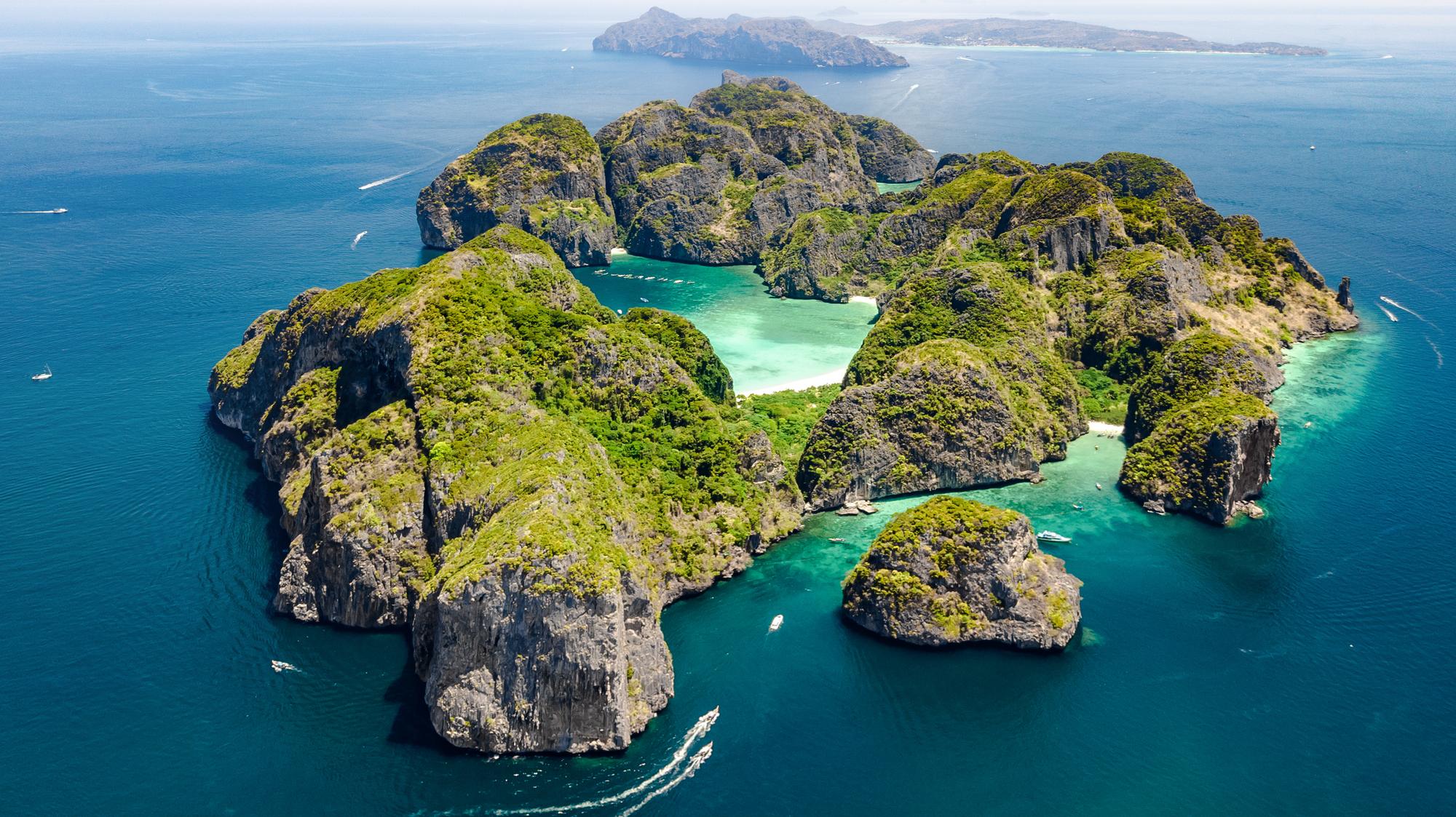 Experience the aerial view of Phi Phi Island Beach in Thailand, showcasing its stunning coastline, pristine shores, and inviting travel destinations | Aerial, coastline, island, travel, shore, Thailand | Fraser