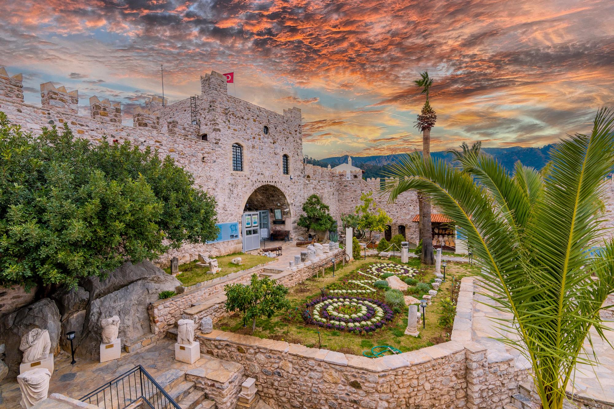 Experience the beauty and history of Marmaris in Turkey, with its majestic castle, picturesque sunrise under cloudy skies, and scenic palm trees | Marmaris, castle, history, beautiful, cloudy, sunrise, palm | Fraser